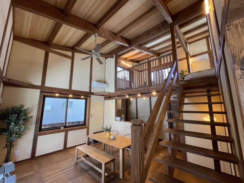 下屋のある家の吹抜けLDK。木の柱と梁、ダイニングテーブルと階段